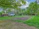 Wide shot of a tree-lined backyard featuring a garden and multiple sheds at 7180 W Sacramento Dr, Greenfield, IN 46140