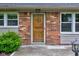 Close-up of a rustic wooden front door flanked by windows, set in a brick facade at 7180 W Sacramento Dr, Greenfield, IN 46140