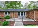 Inviting brick home with a wooden front door, covered porch, and manicured landscaping at 7180 W Sacramento Dr, Greenfield, IN 46140