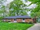 Charming brick home with an attached garage, beautiful lawn, and mature trees at 7180 W Sacramento Dr, Greenfield, IN 46140