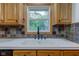 Close-up of the kitchen sink area, highlighting the wooden cabinets and decorative backsplash with laminate floors at 7180 W Sacramento Dr, Greenfield, IN 46140