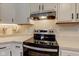 Close-up of the stainless steel stove with range hood and white cabinets at 7634 Pennycroft Dr, Indianapolis, IN 46236