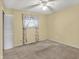 A cozy bedroom featuring carpet floors, a ceiling fan, and a window with floral curtains at 7702 Dornock Dr, Indianapolis, IN 46237