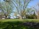 Backyard with mature trees and a pile of burned wood in the foreground at 10360 Wilson Rd, Brownsburg, IN 46112