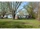 Wide shot of the backyard with mature trees, climb wall, and buildings in the background at 10360 Wilson Rd, Brownsburg, IN 46112