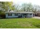 A light blue single-story home with a well-manicured lawn, mature trees, and a paved driveway at 10360 Wilson Rd, Brownsburg, IN 46112