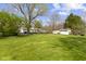 Expansive backyard features lush lawn, mature trees, and detached garage offering ample space for outdoor enjoyment at 10421 Hillsdale Dr, Carmel, IN 46032