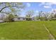 Ranch-style home on lush green lawn with mature trees under a blue sky on a sunny day at 10421 Hillsdale Dr, Carmel, IN 46032