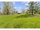 Quaint ranch home on expansive green lawn surrounded by mature trees under sunny skies at 10421 Hillsdale Dr, Carmel, IN 46032