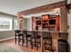 Wet bar features brick arch, granite countertops, custom cabinetry, seating for four, and display shelves in this finished basement at 13682 Frenchmans Creek, Carmel, IN 46032