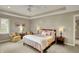 This is a spacious bedroom with a tray ceiling and a ceiling fan, two chairs and a wooden framed bed at 13682 Frenchmans Creek, Carmel, IN 46032
