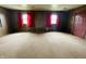 Spacious living room features paneled walls, carpeted floors, and two windows with red curtains at 1387 W Furry Rd, Fountaintown, IN 46130