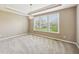 Neutral carpeted bedroom with a tray ceiling, chandelier, neutral color walls, and a large window at 14814 Edgebrook Dr, Fishers, IN 46040