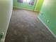 Bedroom with neutral carpeting, green walls, and window; bright, with potential for a cozy space at 1640 Lawton Ave, Columbus, IN 47201