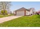 View of the backyard showing a driveway, grassy yard, vinyl siding, and two car garage at 2075 Sea Hero Ct, Indianapolis, IN 46234