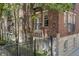 Exterior angle view of a brick apartment building with black metal balconies and a fenced yard at 226 N Cleveland St # 226C, Indianapolis, IN 46204