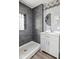 Modern bathroom with gray tiled shower, a white vanity, and a stylish round mirror at 2833 Hervey St, Indianapolis, IN 46203