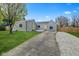 A charming home showcases a light gray exterior and a spacious driveway, enhanced by a vibrant yellow door at 2833 Hervey St, Indianapolis, IN 46203