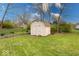 Backyard with shed and a stone wall surrounded by lush green grass and mature trees at 3303 Busy Bee Ln, Indianapolis, IN 46227