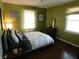Cozy bedroom features warm green walls, hardwood floors, and soft natural light through the window at 4815 Carrollton Ave, Indianapolis, IN 46205