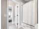 Tiled bathroom with open doorway, showcasing patterned floors and a fresh white shower curtain at 496 Bridgemont Ln, Carmel, IN 46032