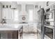 Well-lit kitchen with white cabinets, stainless appliances, an island with seating, and patterned backsplash at 496 Bridgemont Ln, Carmel, IN 46032