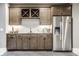 Basement kitchenette featuring stainless steel refrigerator, wooden cabinets, and subway tile backsplash at 496 Bridgemont Ln, Carmel, IN 46032