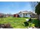 Spacious fenced backyard with lush green grass, mature trees and a wooden deck at 5500 W Sudbury Dr, Muncie, IN 47304