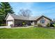 Inviting brick home with a well-kept lawn, featuring mature trees and a welcoming entrance pathway on a sunny day at 5500 W Sudbury Dr, Muncie, IN 47304