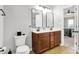 Bathroom with dual sinks, square mirrors, dark cabinetry, and a view into the main bedroom at 5595 Auburndale Dr, Bargersville, IN 46106