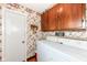 Functional laundry area with upper cabinets and vintage wallpaper, providing practical storage and style at 5927 Pine Hill Dr, Indianapolis, IN 46235