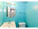 Bright bathroom with blue walls, white fixtures, vanity with sink, round mirror, and lighting at 6017 E 52Nd Pl, Indianapolis, IN 46226