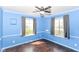 Bright blue bedroom with hardwood floors, ceiling fan, and two windows allowing for plenty of natural light at 6017 E 52Nd Pl, Indianapolis, IN 46226