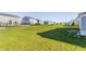 Wide, grassy backyard with neighboring homes in the distance, divided by black metal fencing on a sunny day at 6408 Askin Dr, Indianapolis, IN 46259