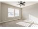 Bright bedroom featuring a ceiling fan, large window, and neutral carpet, offering a comfortable and airy space at 6408 Askin Dr, Indianapolis, IN 46259