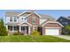 Charming two-story home with a brick and gray siding exterior, attached garage, and a lush front lawn at 6408 Askin Dr, Indianapolis, IN 46259