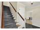 Entryway staircase featuring carpeted steps, wood railing, and a view to the dining room at 70 Williamsburg Ct, Zionsville, IN 46077