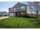 Charming two-story home with green lawn, mature tree, and front porch decorated with an American flag at 717 Driftwood Cir, Danville, IN 46122
