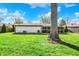 Spacious backyard featuring a mature shade tree, green lawn, and a glimpse of the covered patio at 731 Oak Dr, Greenwood, IN 46142