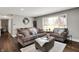 Inviting living room features a brown sofa and chair, wood floors, area rug, and large window letting in natural light at 731 Oak Dr, Greenwood, IN 46142