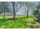 Expansive grassy front yard with mature trees and views of a distant fenced area, providing ample space and natural beauty at 7825 N County Road 650 E, Brownsburg, IN 46112