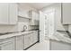 Bright laundry room with granite countertops, white cabinets and gold fixtures at 8083 Easton Ln, Zionsville, IN 46077