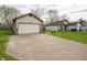 View of the house featuring a two-car garage with neutral siding, brick accents, and a long concrete driveway at 9143 Warwick Rd, Indianapolis, IN 46240