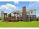 Exterior view of a two-story home featuring a deck, brick chimney and large windows overlooking a well-manicured lawn at 9318 Windrift Way, Zionsville, IN 46077