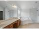Bright bathroom featuring double sinks, a soaking tub, a large mirror, and a separate glass shower at 9318 Windrift Way, Zionsville, IN 46077