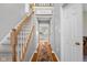 Hallway with hardwood floors leading to staircase and kitchen with white cabinets and modern appliances at 933 Hummingbird Ln, Columbus, IN 47203