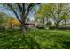 Wide backyard with mature trees surrounding the property, a covered patio, and a charming play area at 961 Parkside Dr, Columbus, IN 47203