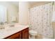 Bright bathroom featuring a vanity with cherry wood cabinets and a shower/tub combo with a floral shower curtain at 10752 Tallow Wood Ln, Indianapolis, IN 46236