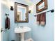 Well-lit powder room featuring a pedestal sink and decorative mirror at 10752 Tallow Wood Ln, Indianapolis, IN 46236