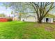 Large backyard with green grass, mature trees, and a storage shed offering outdoor space for leisure and storage at 1213 Fairview Dr, Greenfield, IN 46140
